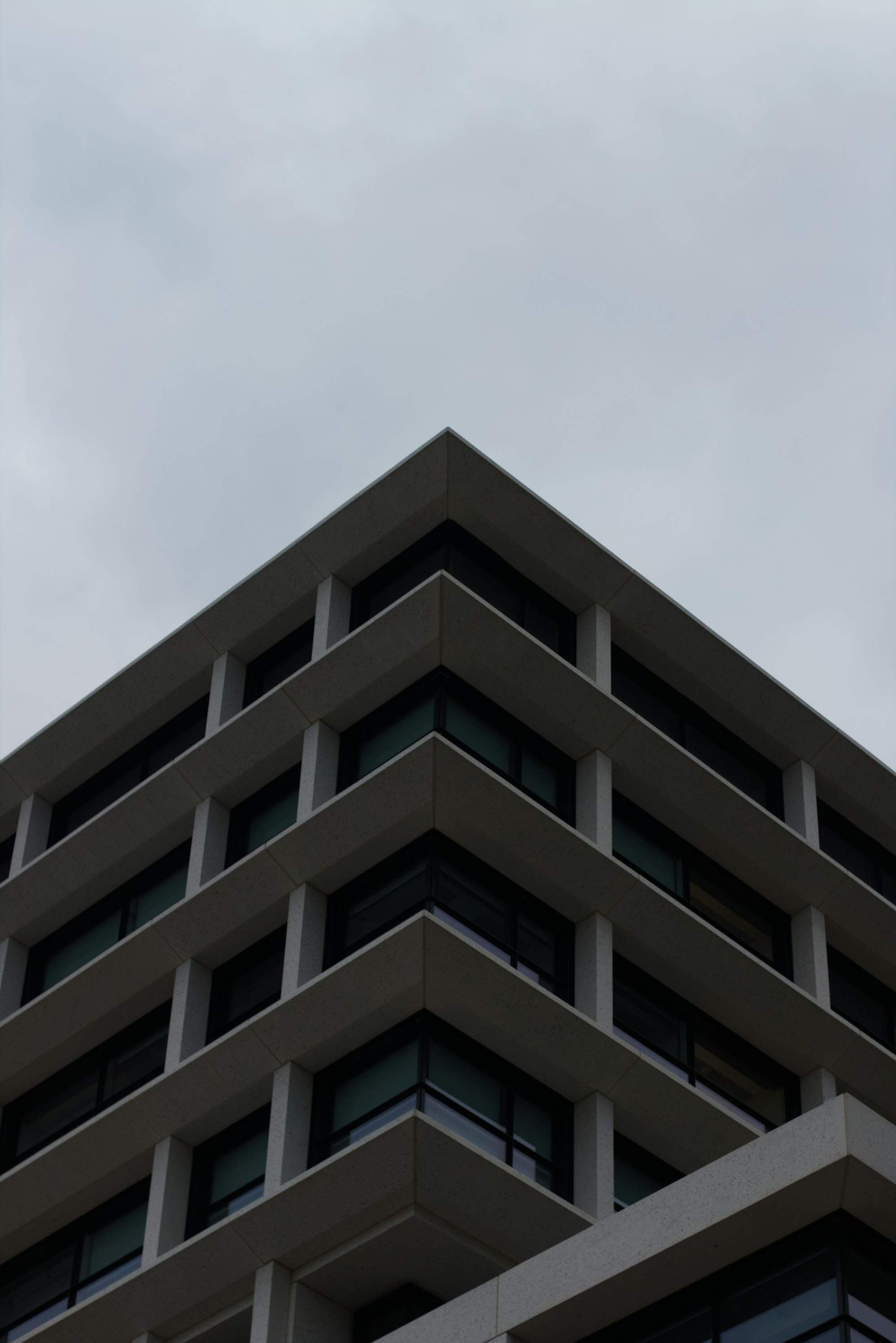 The corner of a concrete office building under an overcast sky