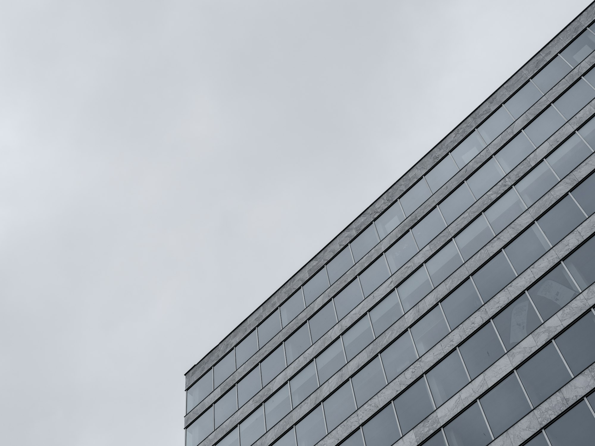 The glass facade of an office building under an overcast sky